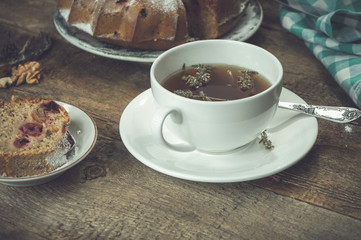 Black tea with thyme and cherry cake on the background