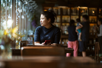 beautiful asian woman hand using smartphone holidays moment at coffeeshop with window light and garden