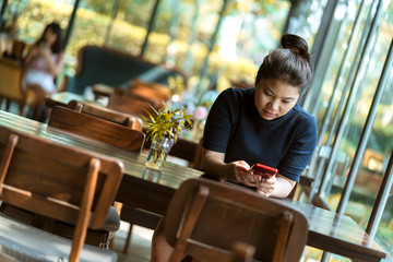 Fototapeta na wymiar beautiful asian woman hand using smartphone holidays moment at coffeeshop with window light and garden
