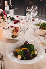 Romantic table setting with wine, beautiful flowers in box, empty glasses, rose petals and candles