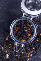 Black tea with natural additives in a glass jar on a dark background