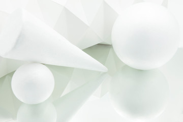 white origami background reflected in mirror with cone and two white spheres of different sizes