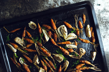 Roasted fennel and baby carrots on tray. Rustic background.