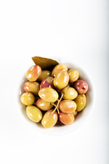 Green olives in bowl with leave of Daphne