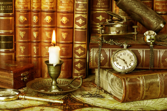 Pocket watch, burning candle and old books