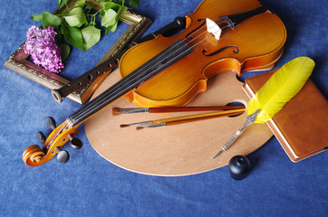 Still life with the attributes of art. Violin, palette, brushes, a bouquet of lilac