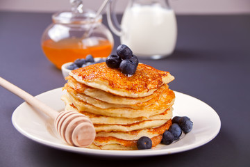 Pancakes with berries and honey on the black background