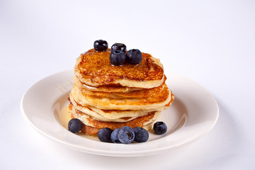 Pancakes with berries and honey on the white background