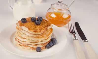 Pancakes with berries and honey on the white background