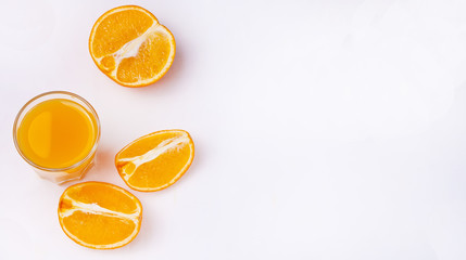 Glass of orange juice and slices of orange fruit on white background. Flat lay. Copy space.