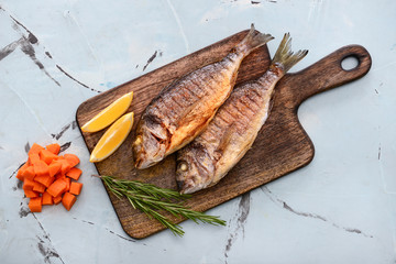 Board with grilled dorado fish on color background