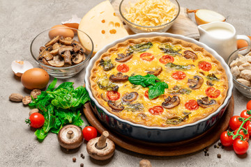 Baked homemade quiche pie in ceramic baking form, eggs and cream