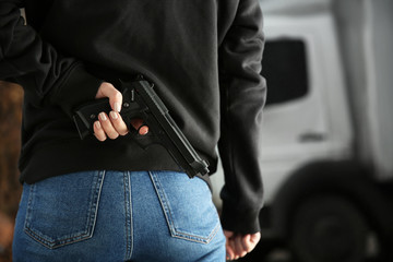 Woman hiding gun behind back outdoors