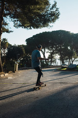 Man practicing with his long board on a lonely street in a sunset