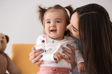 Young woman with her cute little daughter sitting in armchair