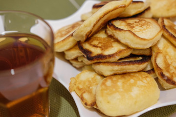 A stack of fritters on a white plate on the table.