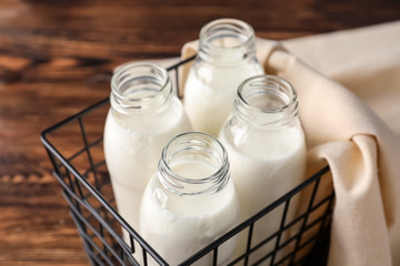 Box with bottles of fresh milk on wooden table