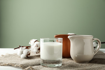 Glass and jugs of fresh milk on table