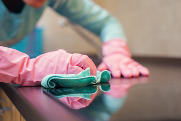 Image of female hands in pink gloves washing hob