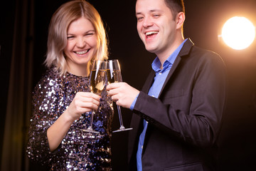 Photo of smiling woman in brilliant dress and men with wine glasses with champagne on black background