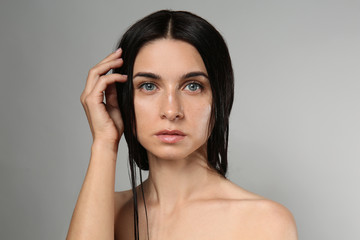 Portrait of beautiful young woman with natural makeup on grey background