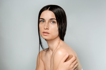 Portrait of beautiful young woman with natural makeup on grey background