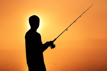 silhouette of fisherman with fishing rod and reel