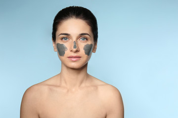 Portrait of beautiful young woman with facial mask on color background