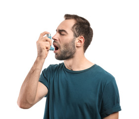 Young man with inhaler having asthma attack on white background