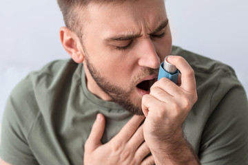 Young man with inhaler having asthma attack at home