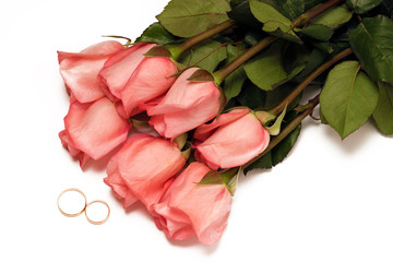 Wedding rings and a bouquet of pink roses on a white background top view. Valentine's day, International Women's day, wedding concept