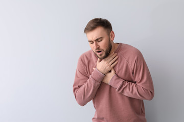 Young man having asthma attack on white background