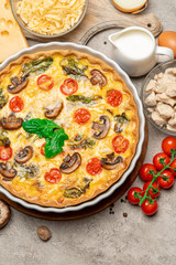 Baked homemade quiche pie in ceramic baking form, eggs and cream