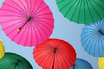 Collection of multi colored umbrellas hanging up.