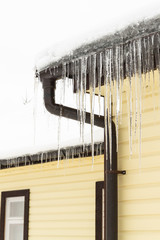 Icicles hang from the roof of a private house in winter