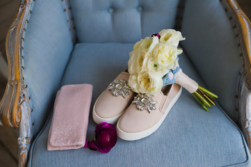 white Bridal bouquet, shoes and a bride's handbag on a blue chair