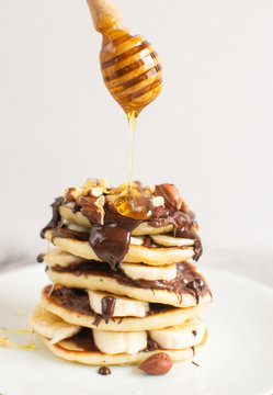 Homemade Pancakes with Chocolate Cream Sauce Banana Walnuts Easy Food Concept Gray Background