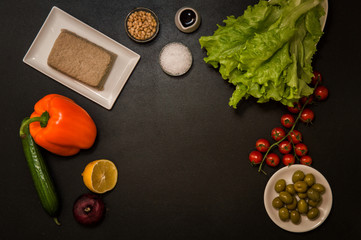 Flat lay. Italian food. Plant based ingredients for vegan greek salad on black background. Copy space.