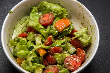 Macro. Italian food. Appetizing vegetable salad flavored with pesto. Black background.