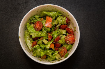 Flat lay. Macro. Italian food. Vegetable salad flavored with pesto. Black background.