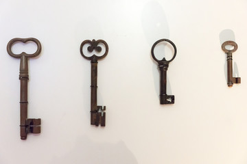 Four old rusty keys on the bright house wall