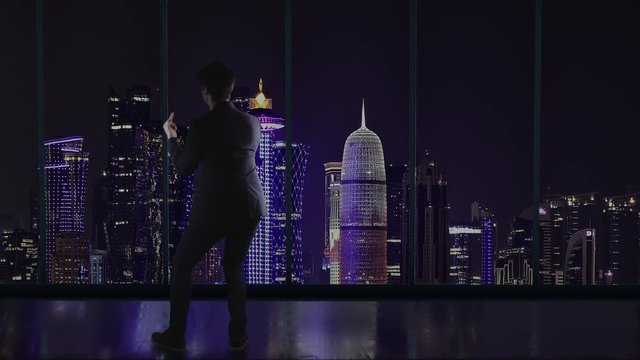Silhouette of an arrogant businessman in the office standing in front of a big window with a view of Doha, Quatar and showing the middle finger