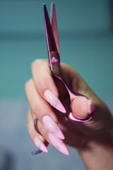 Female hands with long, well-groomed nails with Scissors