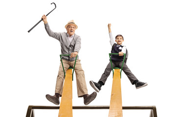 Cheerful grandpa and his grandson having fun on a seesaw