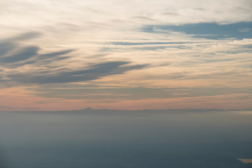 Naklejka na ściany i meble Aerial view at sunset or sunrise of a fog covered plain with mountain in the background