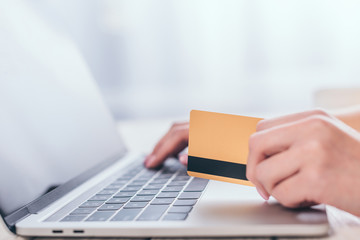 selective focus of credit card in hand of woman using laptop