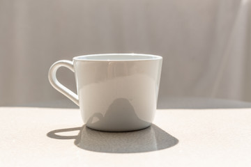 White ceramic coffee cup on white ceramic table, outdoor on sunny day