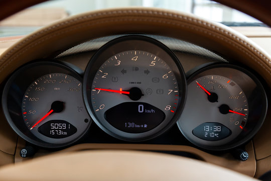 Dashboard Is Covered In Beige Genuine Leather Of A Sports Car Brand Porsche With Instruments Speedometer And Tachometer Displays Are Highlighted On A Black Background With A Red Dial And And An Arrow.