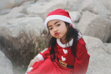 Fototapeta na wymiar Close-up head shot of Little Asian girl in Santa Claus dress.Be blow kiss and playing with camera.