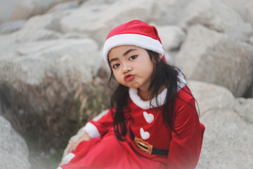 Close-up head shot of Little Asian girl in Santa Claus dress.Be blow kiss and playing with camera.